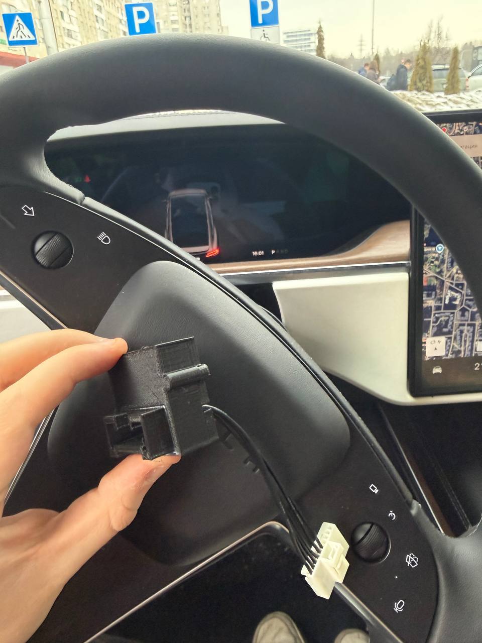 Tesla Free Supercharger Device held in front of a Tesla steering wheel and dashboard